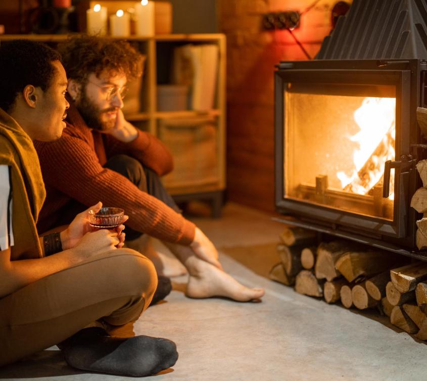 Two people sat by a lit stove