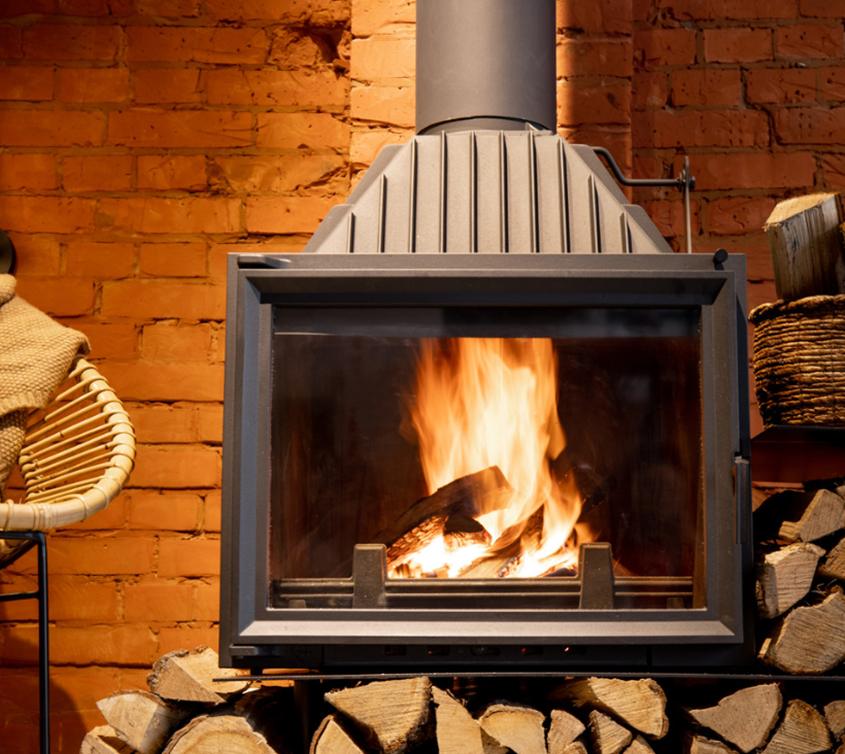 Log burner alight against a brick wall